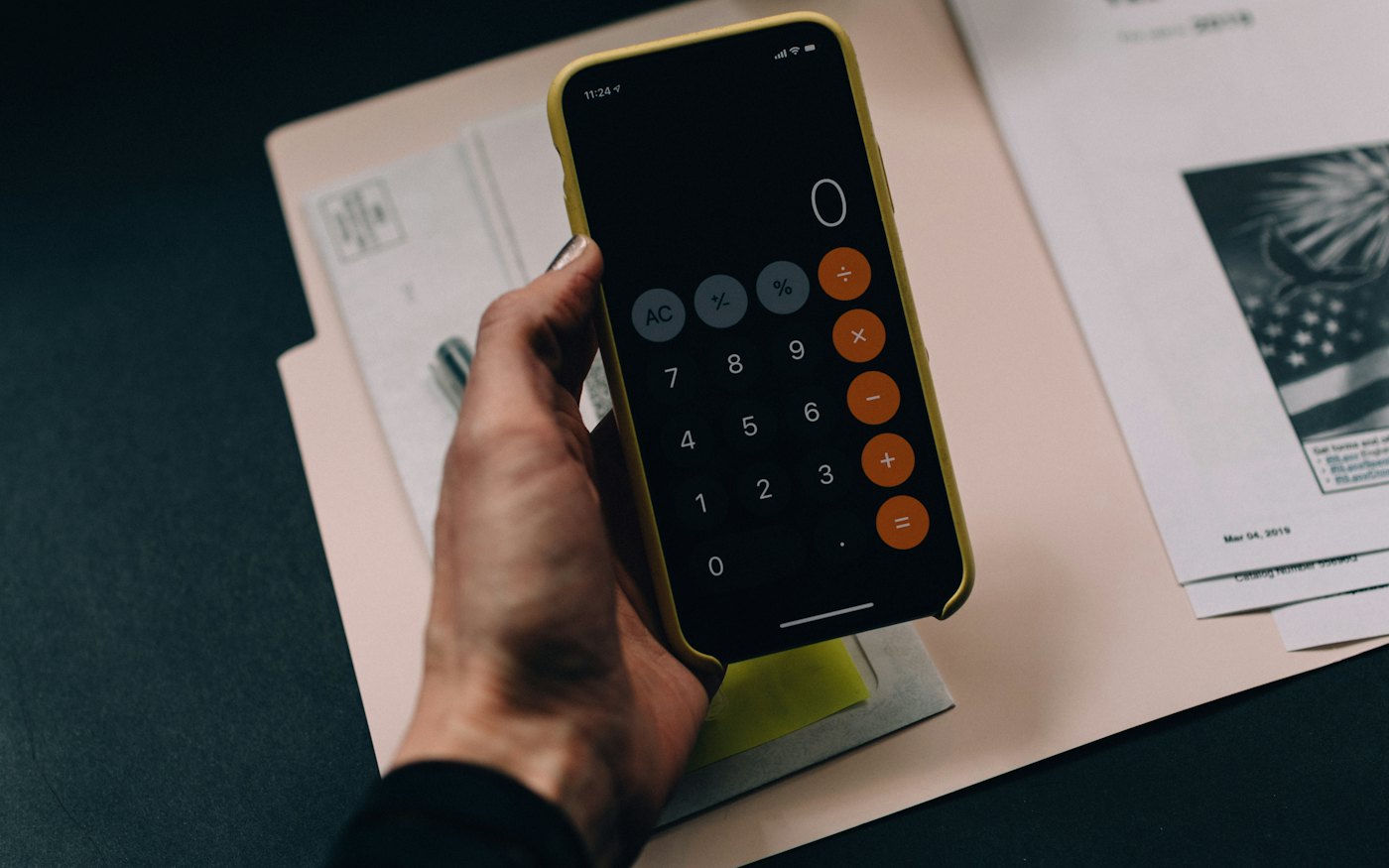 Bir klasörün üzerinde telefonundaki hesap makinesini kullanan el